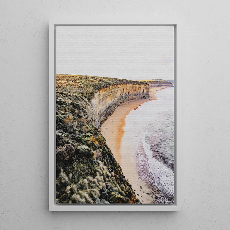 Framed artwork of a coastal landscape with cliffs and beach.
