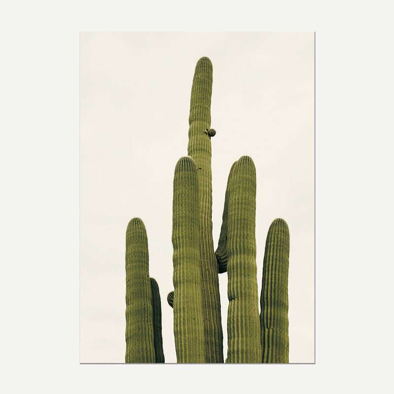 A vertical art print depicting a saguaro cactus with tall green arms against a warm off-white background, shown as a mockup with a subtle drop shadow on a light gray canvas.