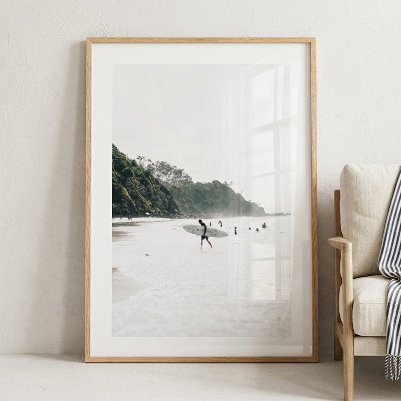 Framed beach photograph on a wall next to a beige armchair.