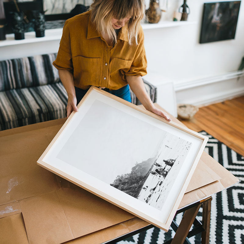 Person holding a framed black and white photograph in a living room setting