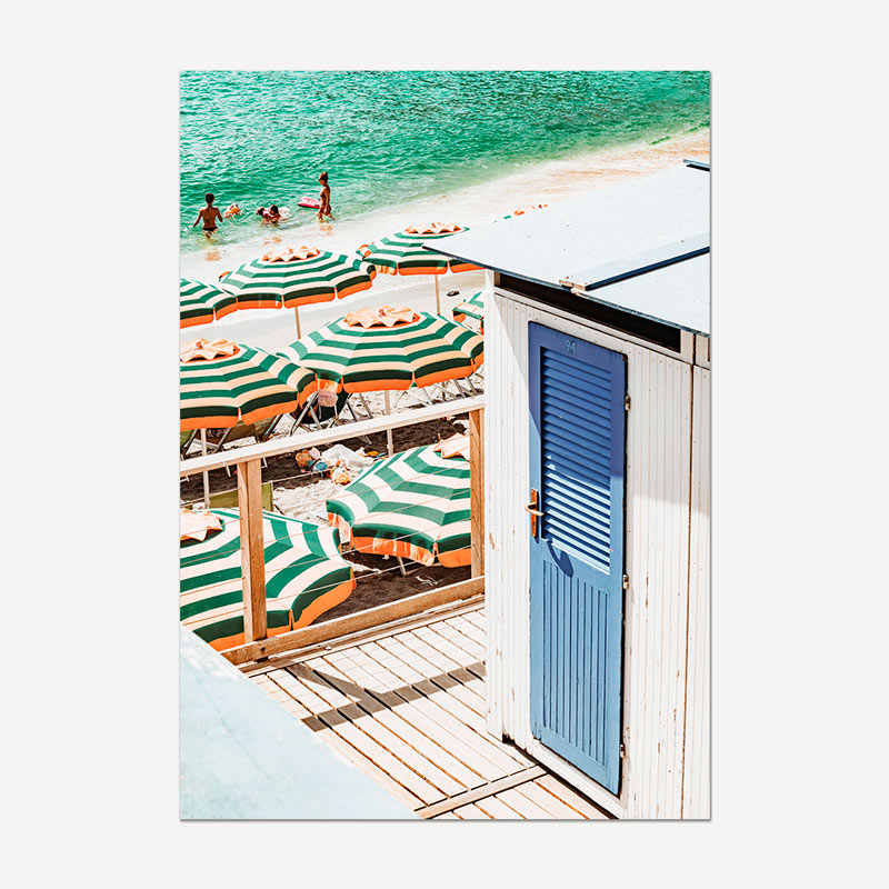 Beach scene with green and white striped umbrellas and a blue door.