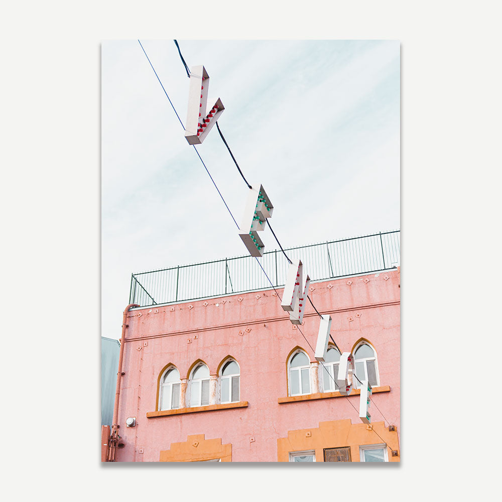 A photograph of the Venice Beach sign in Los Angeles, California, with a pink building in the background, capturing the essence of the beachside location.