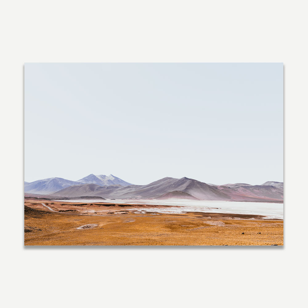 A landscape photograph featuring a desert scene with mountains in the background, predominantly orange and blue colors.