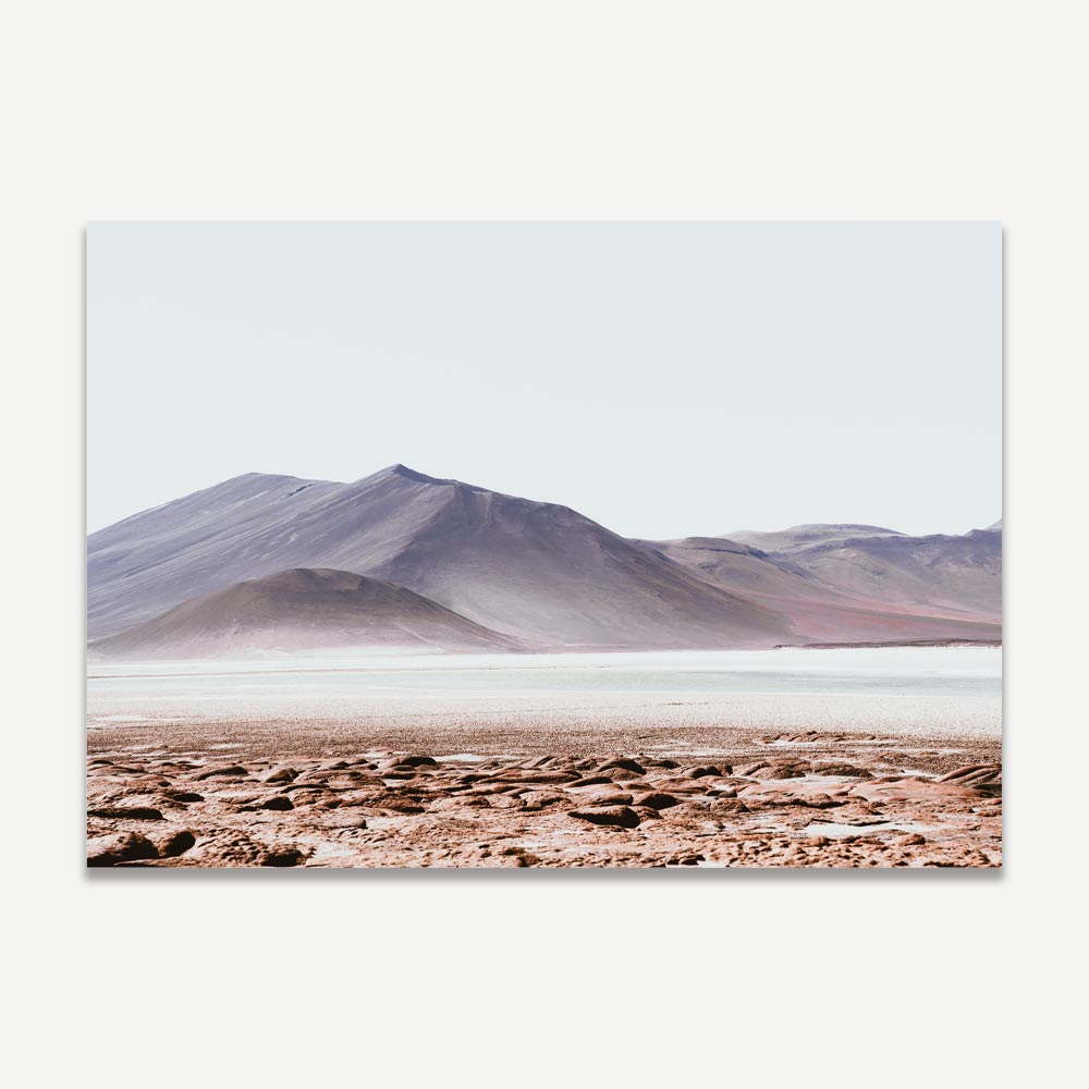 A landscape photograph featuring a desert scene with mountains in the background, predominantly in shades of blue and white.