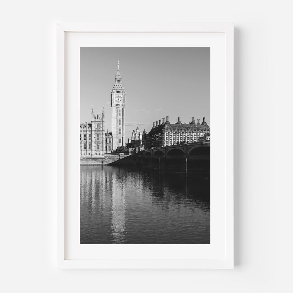A black and white photograph of Westminster Abbey and Big Ben across the Thames River, presented in a vertical format.