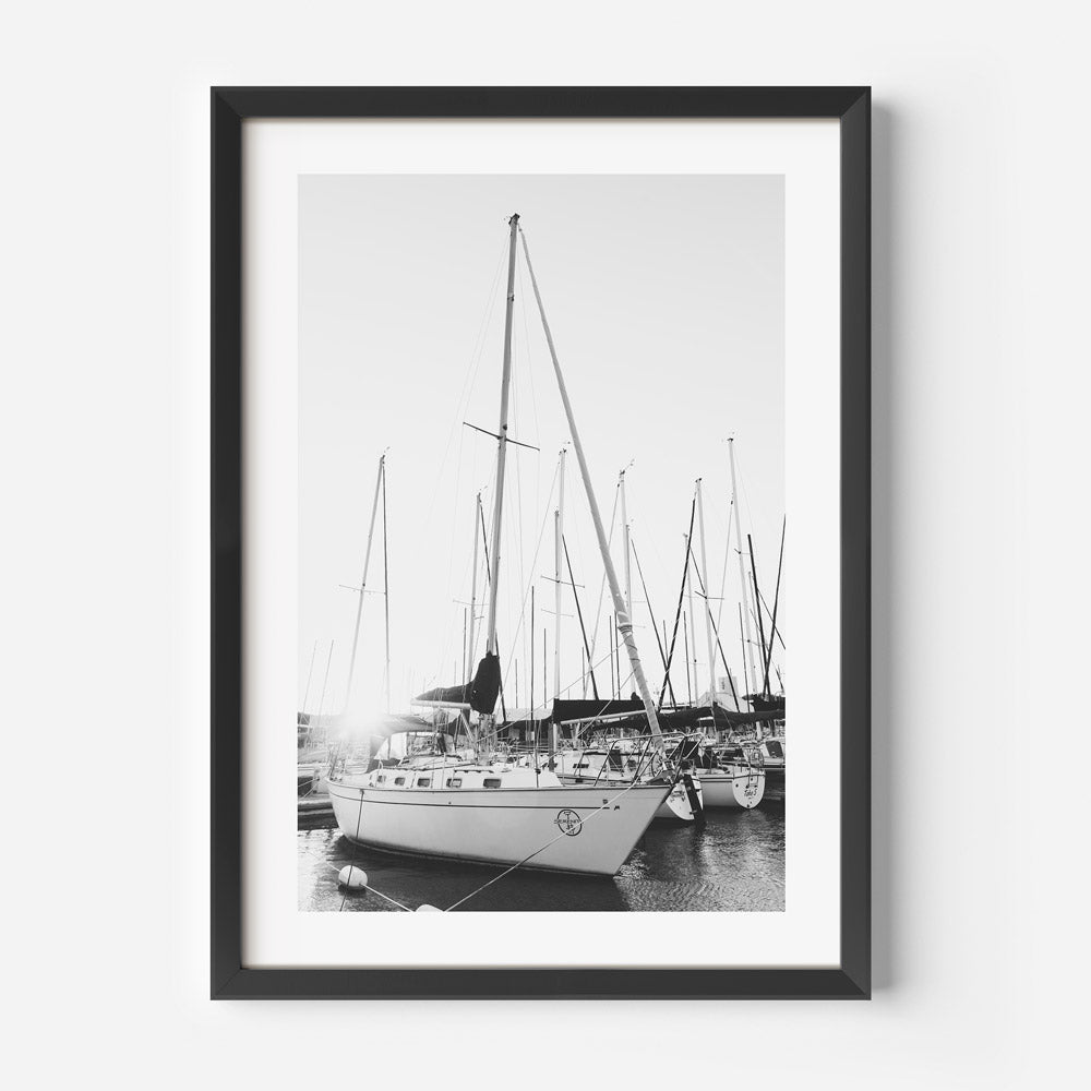 Black and white photograph of a yacht in a marina, displayed in black frame.