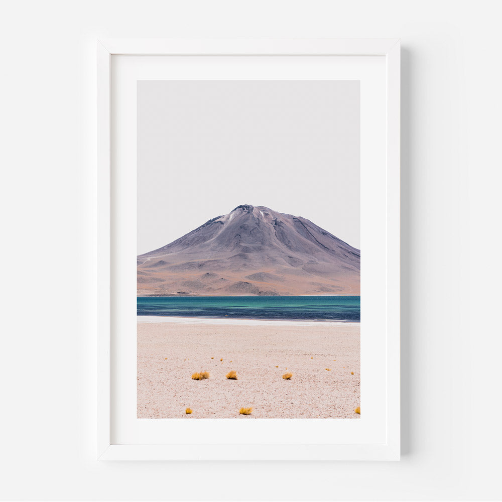 A framed and matted print featuring a landscape photograph with a volcanic mountain in the foreground and a sky with clouds at the top. The color palette is mainly gray and blue.