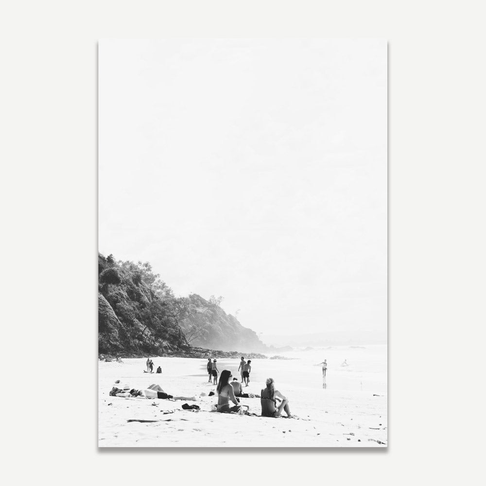 Black and white photograph of a beach scene with people and beachgoers, capturing a moment of leisure.