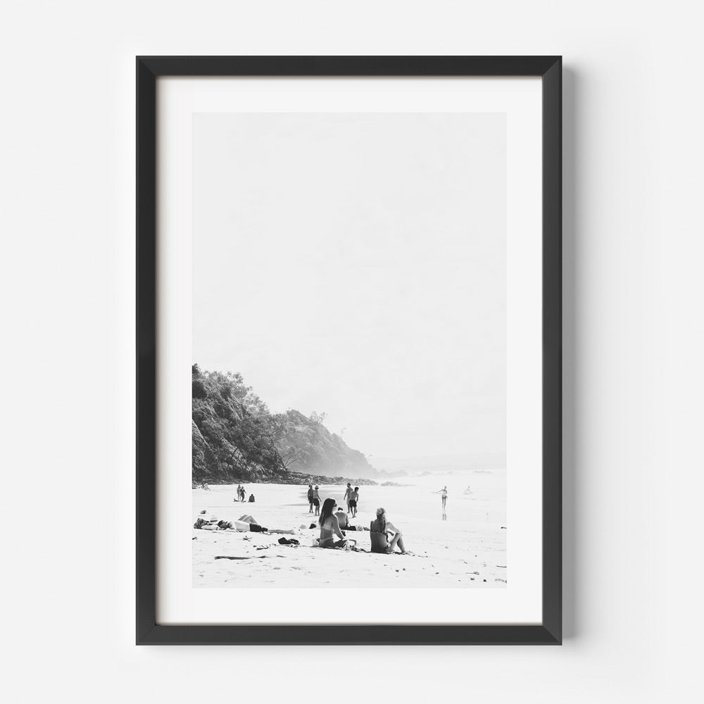 Black and white photograph of a beach scene with people in the distance, framed in a black frame.