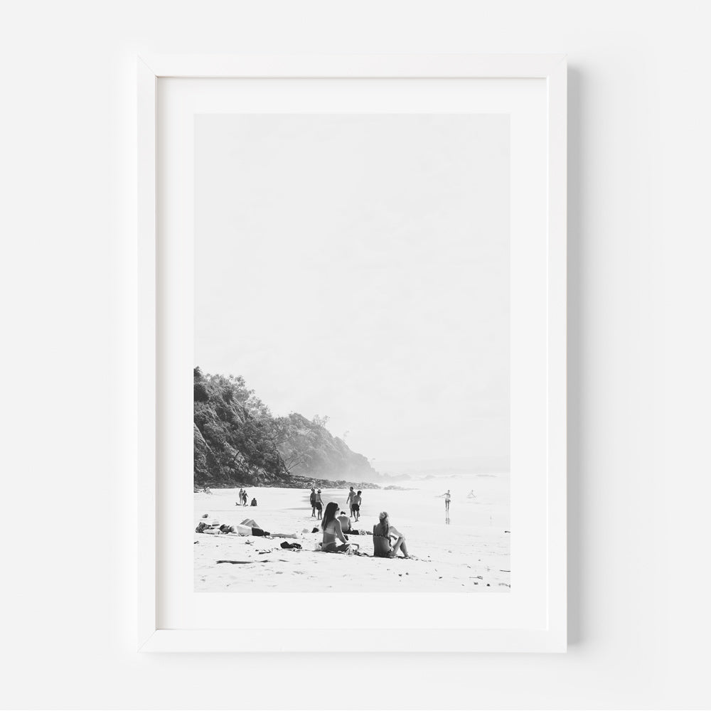 Black and white photograph of a beach scene with people in the distance, framed in a white frame.