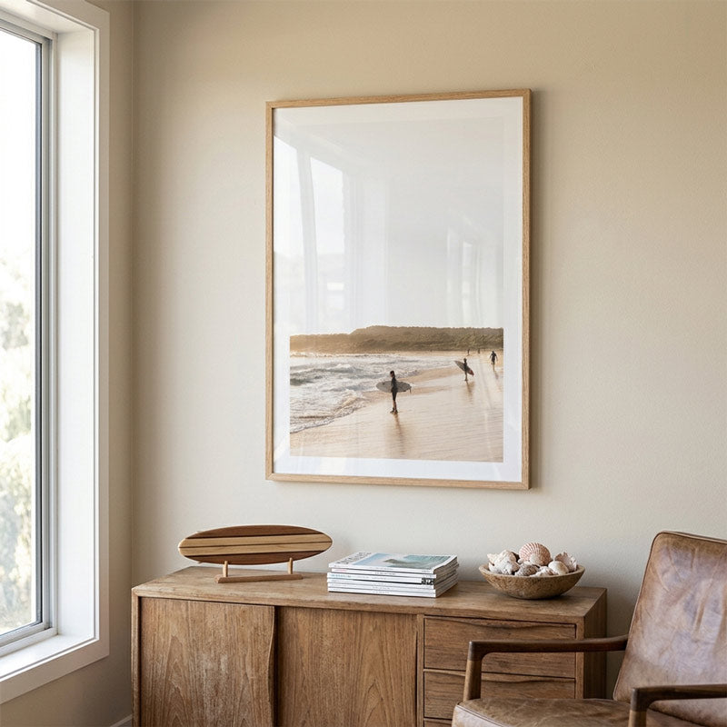 Framed beach scene art on a wall above a wooden desk with decor items.