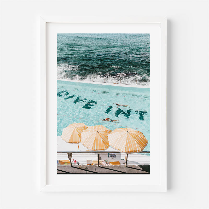 Framed artwork of a pool with 'Dive In' text and umbrellas, featuring a beach scene.