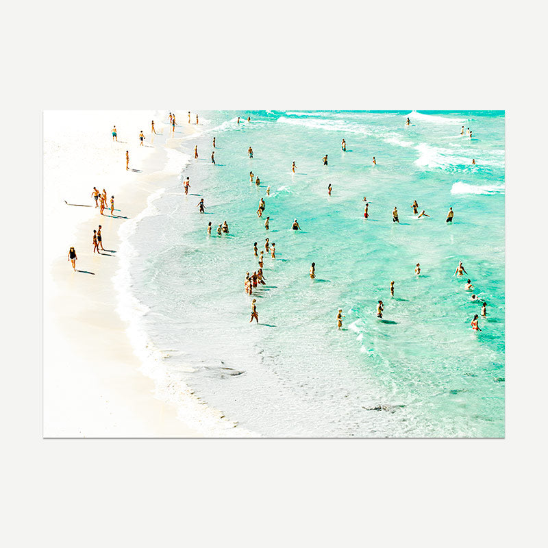 People enjoying a beach with clear turquoise water and white sand.