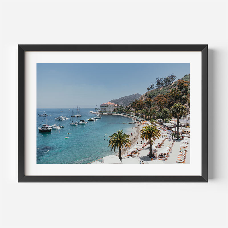 Framed photograph of a coastal scene with boats, palm trees, and a beach.