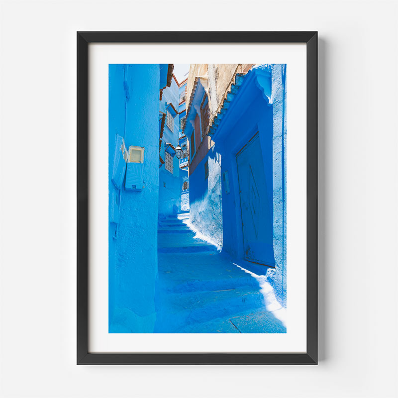 Framed photograph of a blue alleyway on a white wall