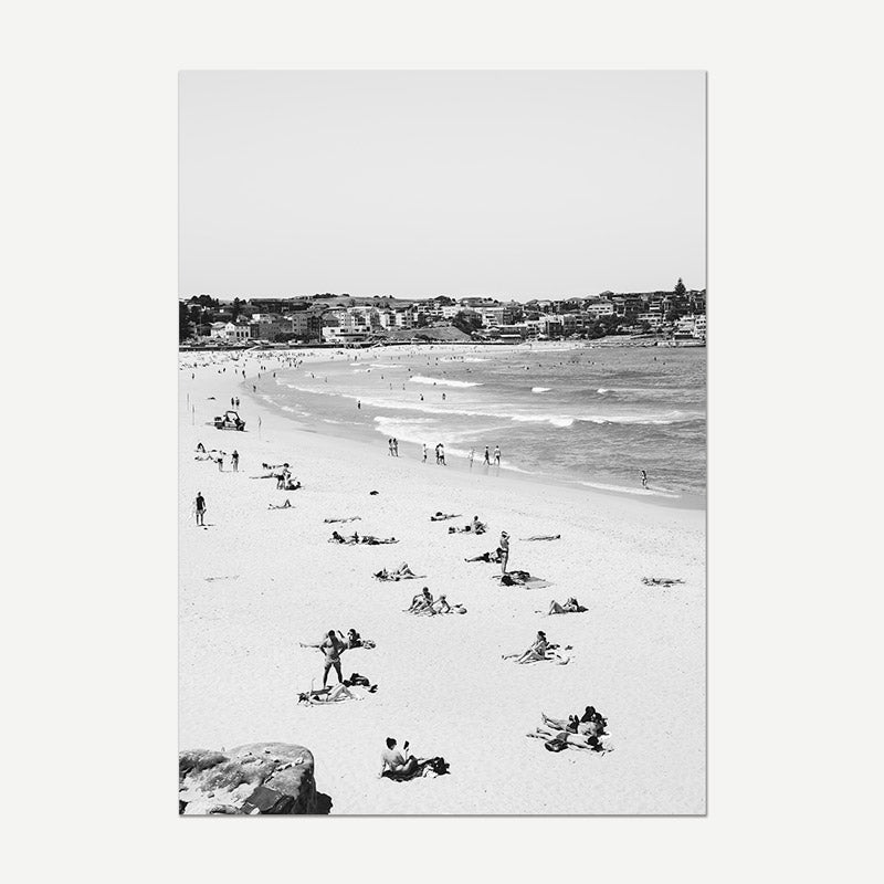Black and white photo of a beach scene with people enjoying the sun and water.