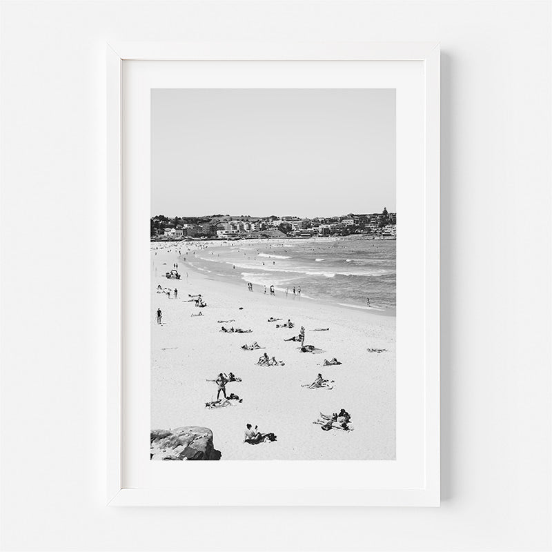 Framed black and white beach scene with people enjoying the sun and sea.