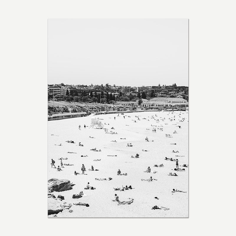 Black and white photo of a crowded beach with people enjoying the sun and sea.