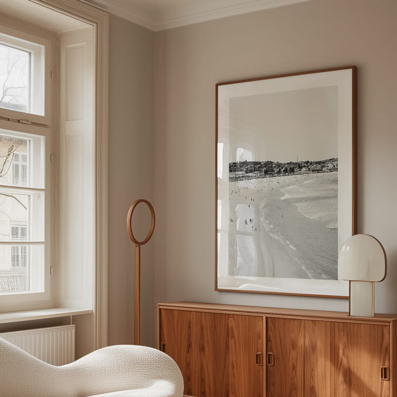 Modern interior with wooden cabinet, framed beach photo, and white chair.