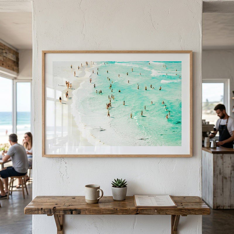 Framed artwork of a beach scene on a wall in a home setting.