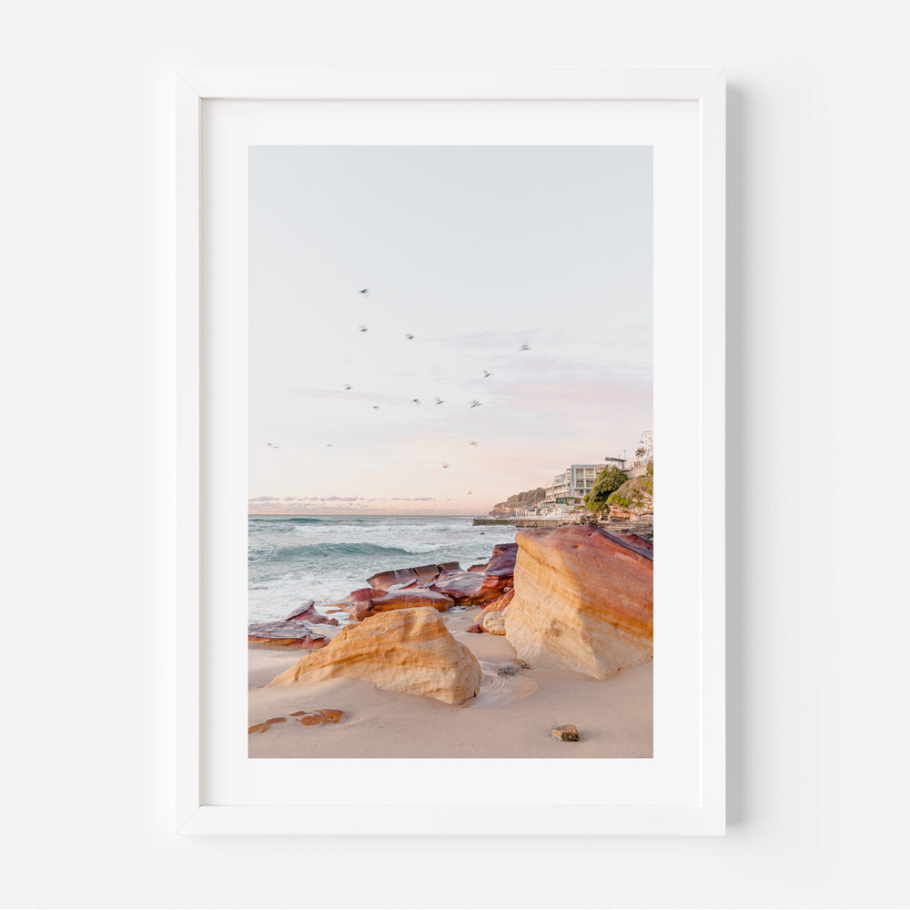 White framed photo of beach with birds flying over it, morning at Rocks Bondi Beach Australia.