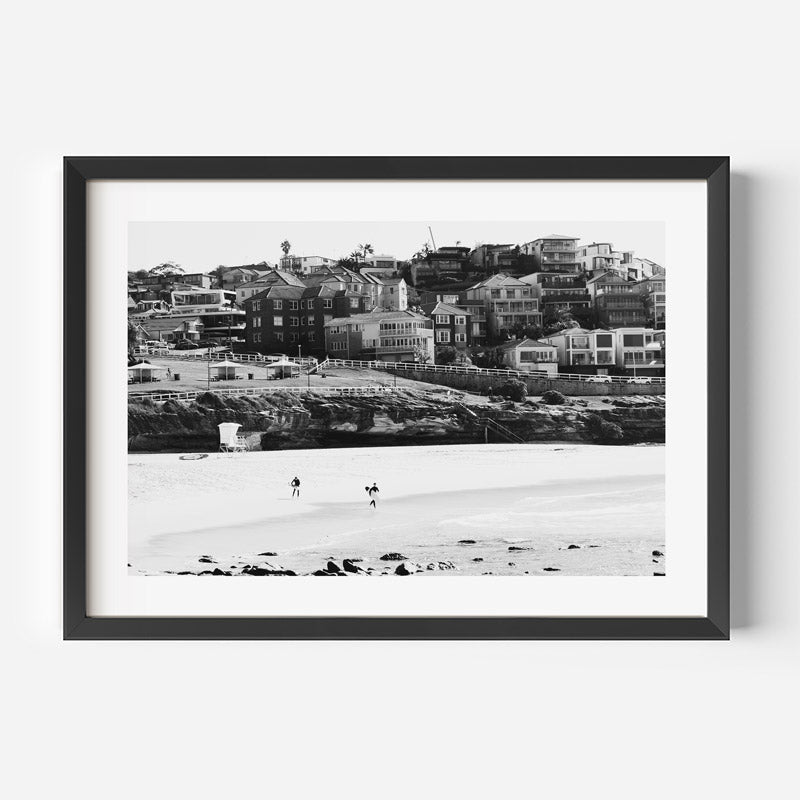 Framed black and white photograph of a coastal scene with houses and people on a beach.