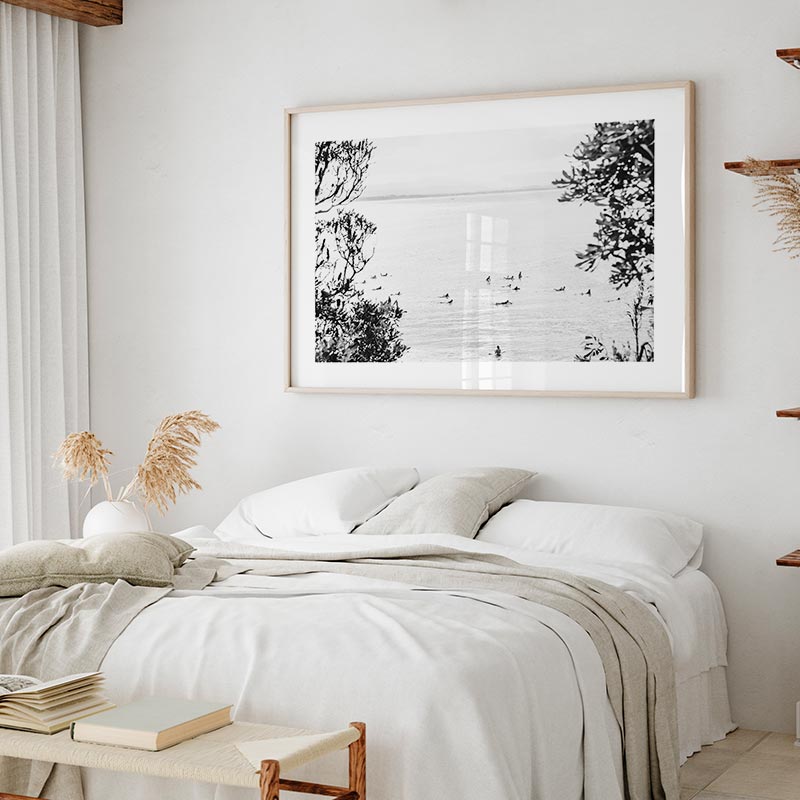 Neatly made bed in a bedroom with a large framed black and white print on the wall.