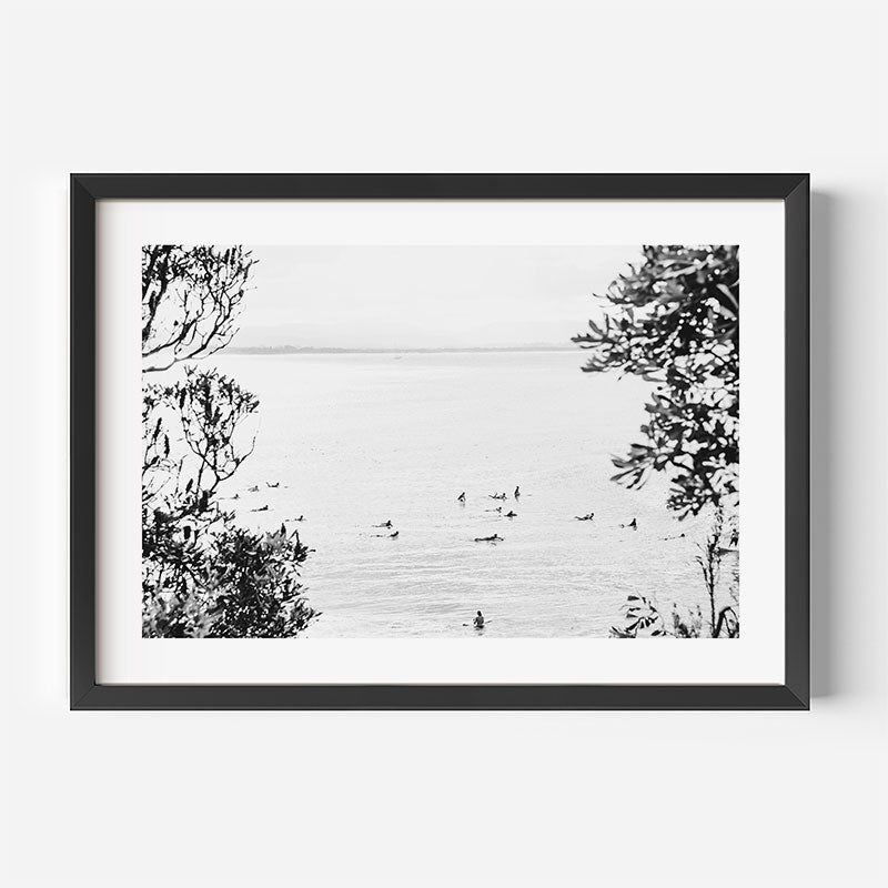 Framed black and white artwork of trees and water on a white wall