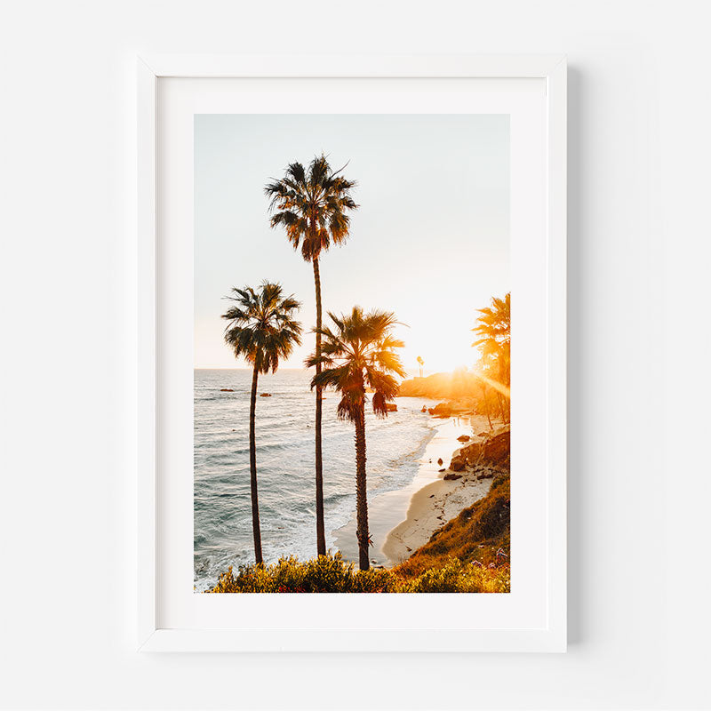 Framed artwork of a beach scene with palm trees and sunset.