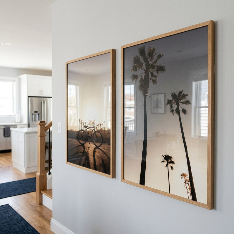 Two framed artworks of palm trees on a wall in a home setting.