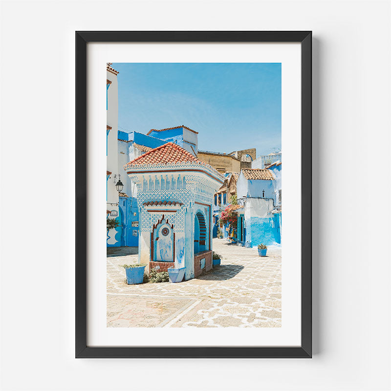 Framed photograph of a colorful street scene with blue and white buildings.