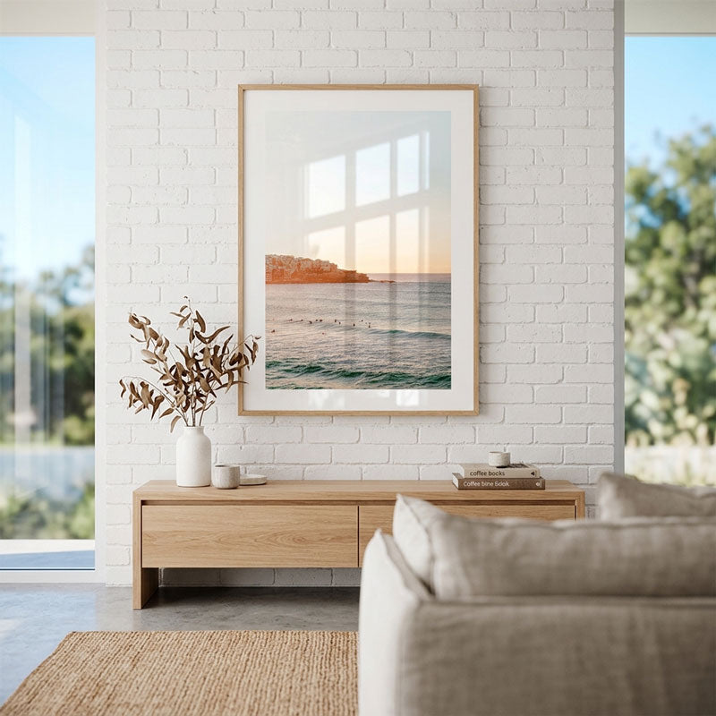 Living room with a framed landscape print on a white brick wall, wooden side table, and beige sofa.