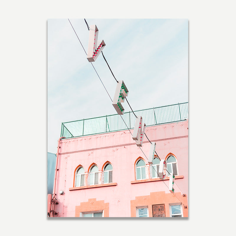 Pink building with green railing and cables against a light blue sky