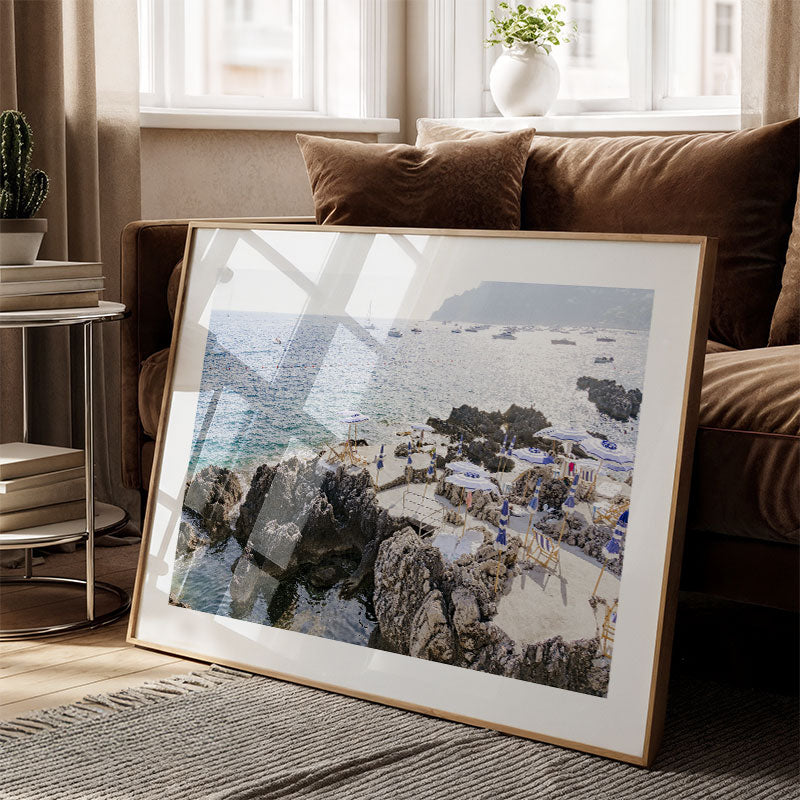 Framed photograph of a coastal scene on a living room floor.