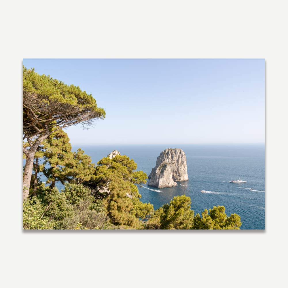Capri's iconic Faraglioni rocks rising from the Mediterranean Sea, captured from Belvedere Tragara with lush greenery and blue sea and sky, embodying natural beauty and Italian elegance.