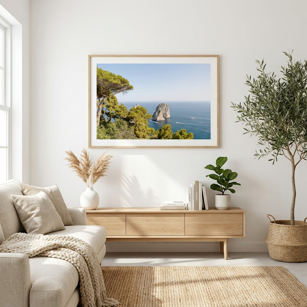 Living room with a framed picture of a coastal scene, a sofa, and decorative plants.