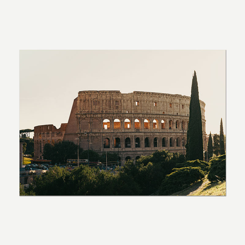 A rectangular wall art print showing the Colosseum in Rome at golden hour, with trees in the foreground, displayed against a light gray background.