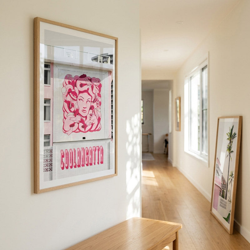 Framed artwork on a wall in a well-lit room with large windows.