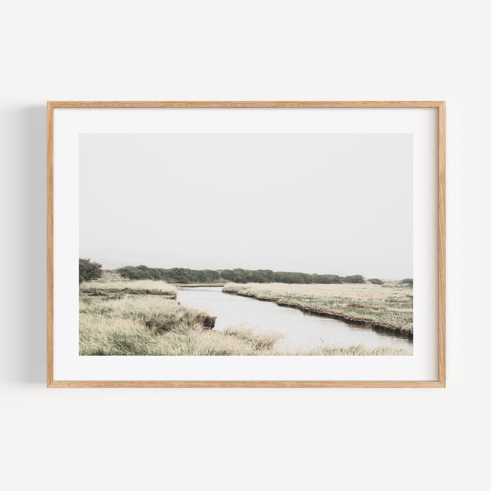 Immerse yourself in the tranquility of the English countryside with this captivating wall art of a river in a field.