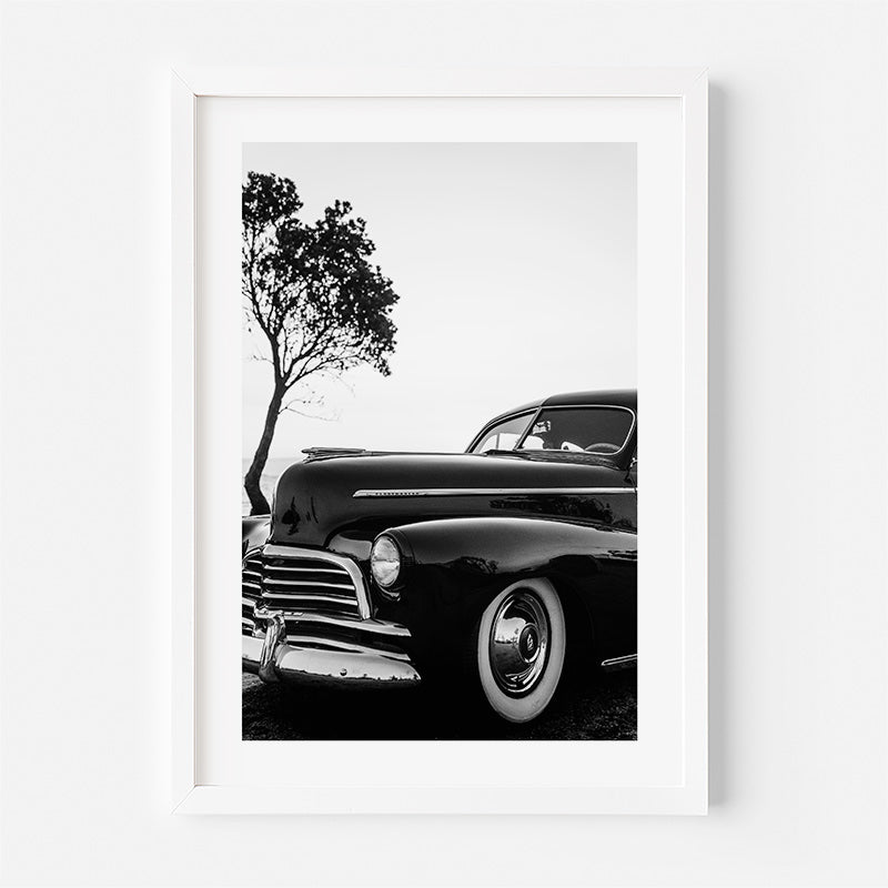 Framed black and white photograph of a classic car with a tree in the background.