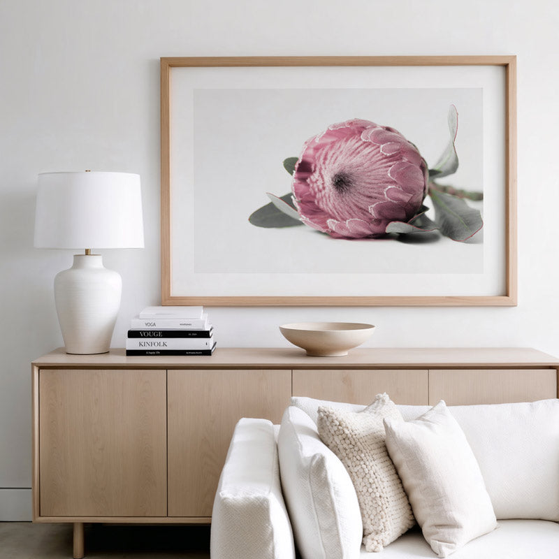 Living room with a wooden sideboard, white sofa, and floral artwork on the wall.