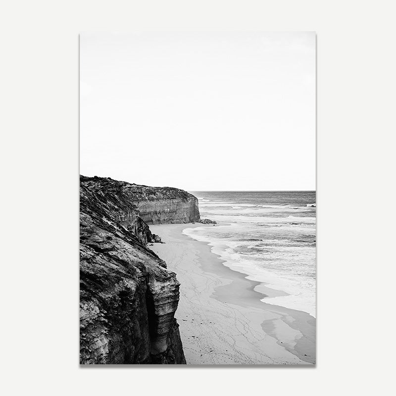 Black and white photograph of a coastal landscape with cliffs and beach.