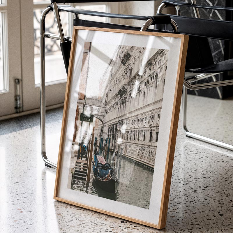 Framed photograph of a canal scene with gondolas on a speckled surface.