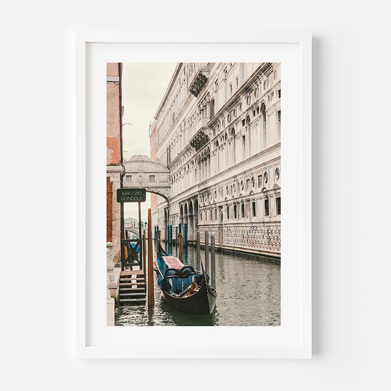 Framed photograph of a gondola on a canal in Venice with a building in the background.