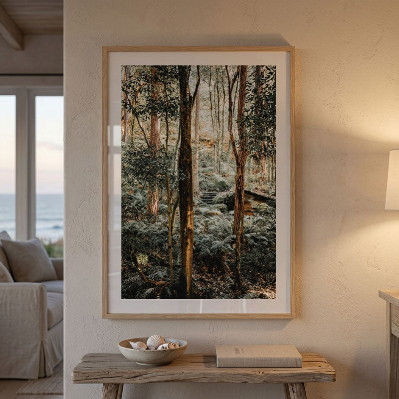 A framed forest art print hangs on a textured beige wall above a rustic wooden console table in a styled living room setting.
