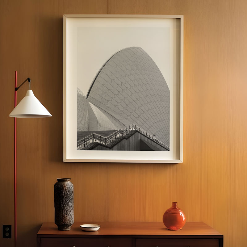 Framed artwork on a wall with a lamp and decorative items below.