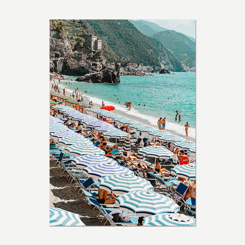 Beach scene with striped umbrellas and chairs, people enjoying the sun, and a scenic background.