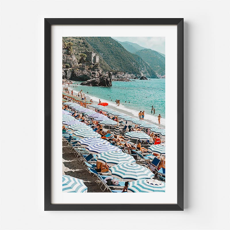 Framed photograph of a beach scene with striped umbrellas and people enjoying the sun.