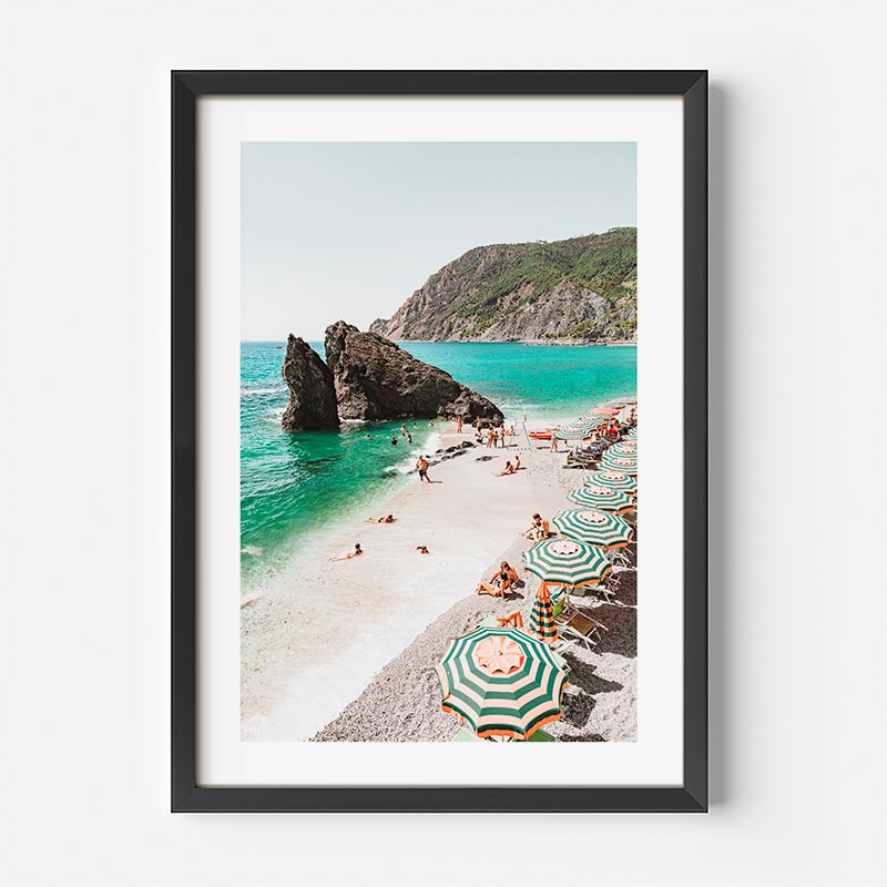 Framed photograph of a beach scene with people and umbrellas.