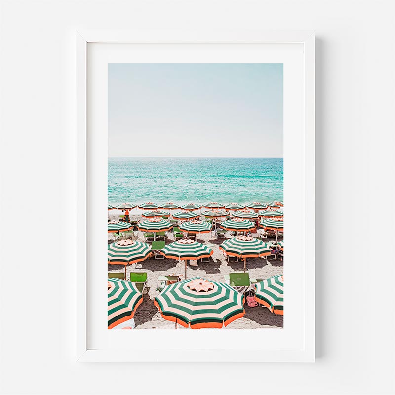 Framed photograph of a beach scene with green and orange striped umbrellas.